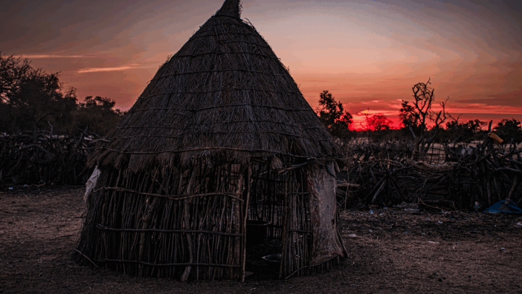 An unelectrified rural home in Senegal with a beautiful sunset behind it